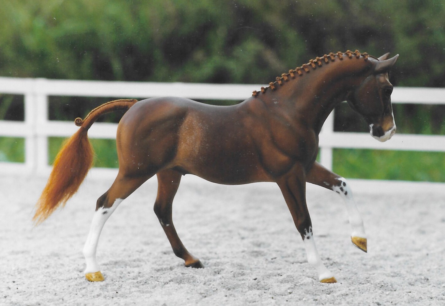 A chestnut model pony with white markings and a braided hair mane and tail